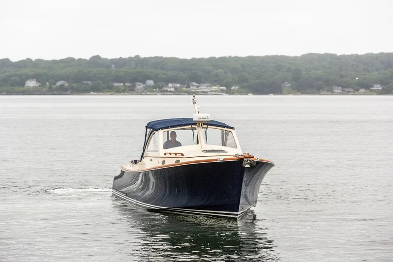 Belle Yacht Photos Pics 1998 Hinckley Picnic Boat cruising on calm waters near a forested shoreline.