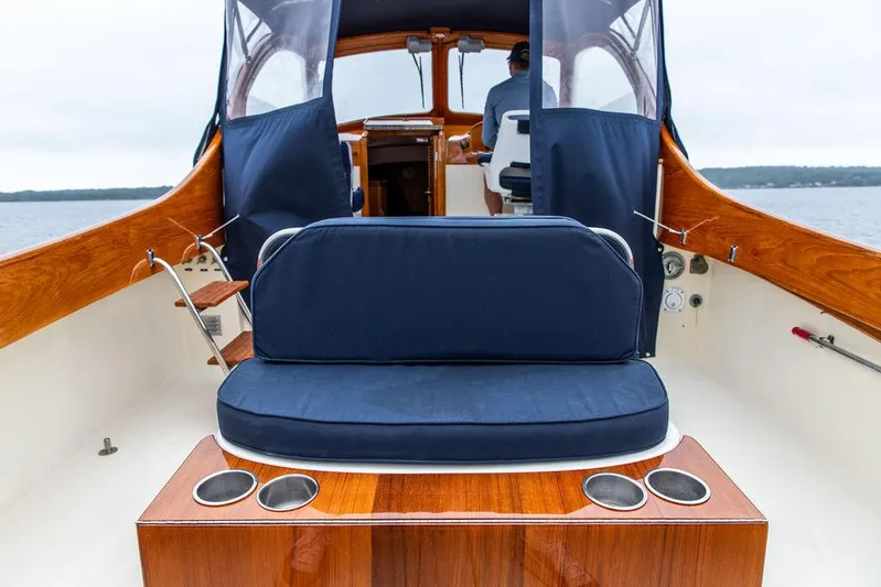 Belle Yacht Photos Pics 1998 Hinckley Picnic Boat interior with blue seating and wooden accents on a calm water backdrop.