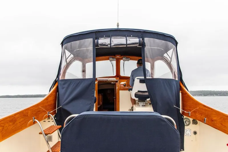 Belle Yacht Photos Pics 1998 Hinckley Picnic Boat interior with wooden accents and blue canopy on a calm waterway.