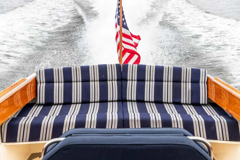 Belle Yacht Photos Pics 1998 Hinckley Picnic Boat with striped seating and American flag, cruising on water.