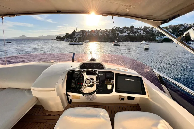  Yacht Photos Pics Cockpit view of 2015 Princess Flybridge 52 Motor Yacht at sunset, overlooking serene bay.