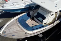 2010 Rhea 35 Open boat with blue seating and wooden deck, docked beside another vessel.