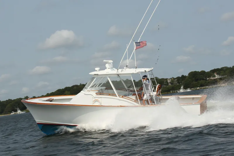 Charmer Yacht Photos Pics 1985 Rybovich 32 Express Walkaround Sportfish cruising on open water, American flag flying.