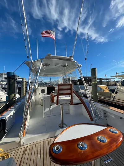 Charmer Yacht Photos Pics 1985 Rybovich 32 Express Walkaround Sportfish boat with American flag, docked under blue sky.