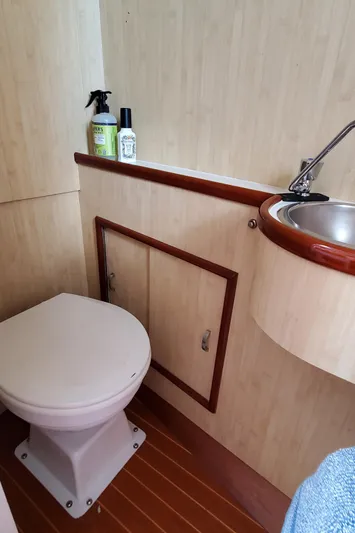 Charmer Yacht Photos Pics 1985 Rybovich 32 Express Walkaround Sportfish bathroom with toilet, sink, and cleaning supplies.