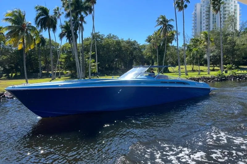 Jam Yacht Photos Pics Blue 2013 Magnum 51 Bestia boat cruising on a sunny day with palm trees in the background.