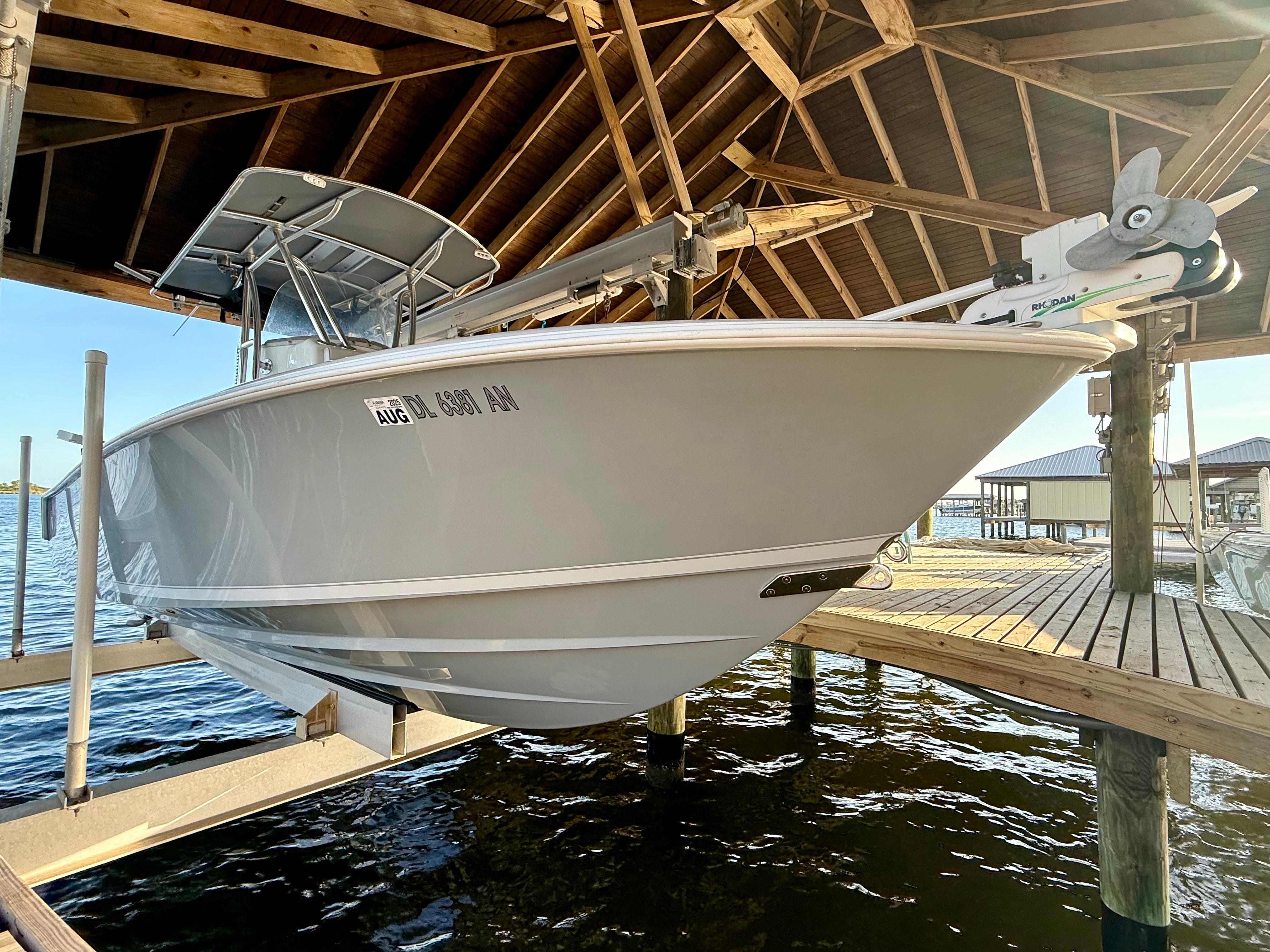 2022 Contender 25T boat docked under wooden shelter by the water.