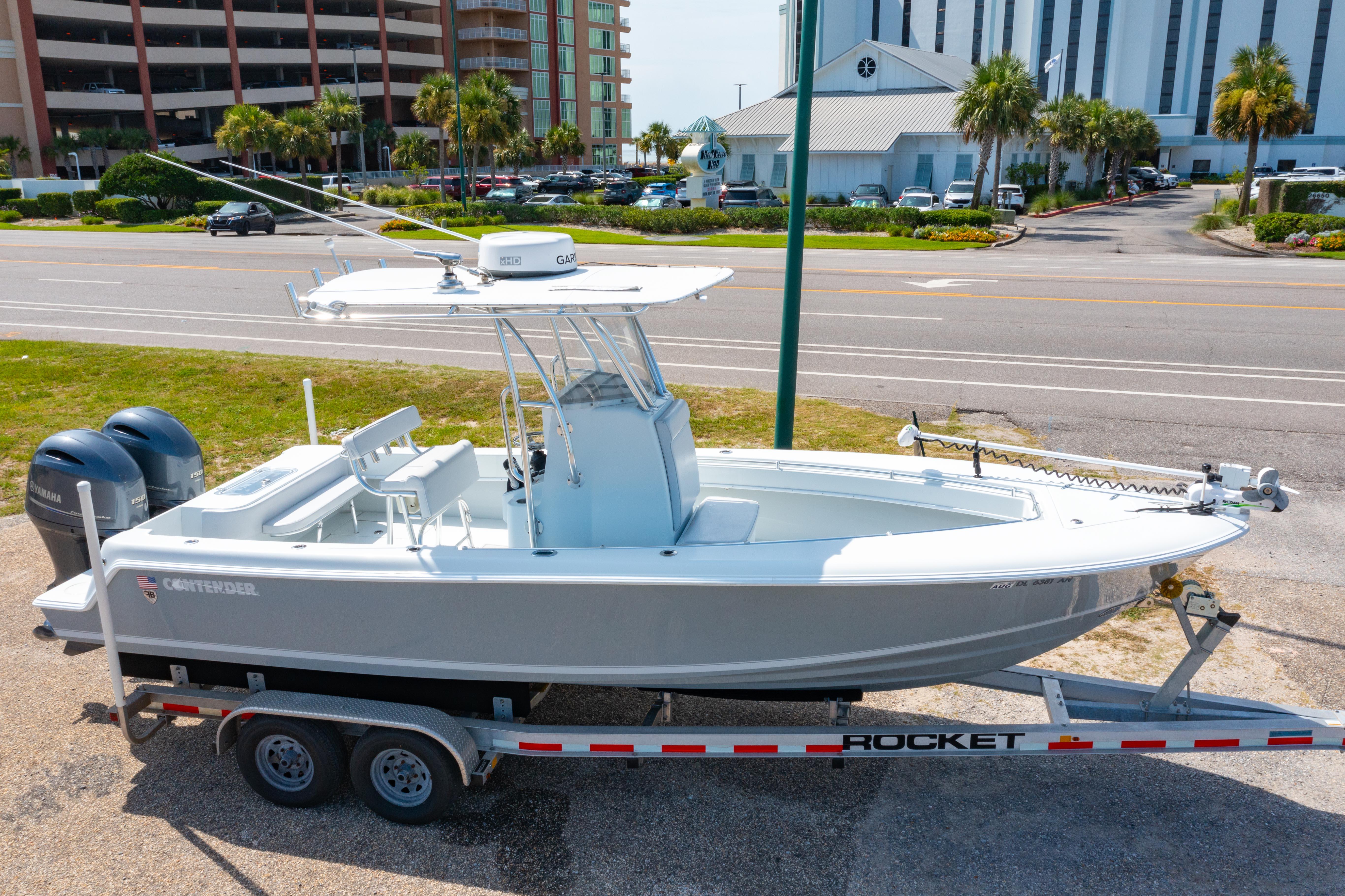 2022 Contender 25T boat on trailer, parked near a road with buildings in the background.