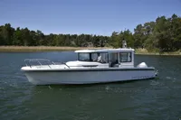 2023 Nimbus C9 boat cruising on a serene lake with lush green trees in the background.