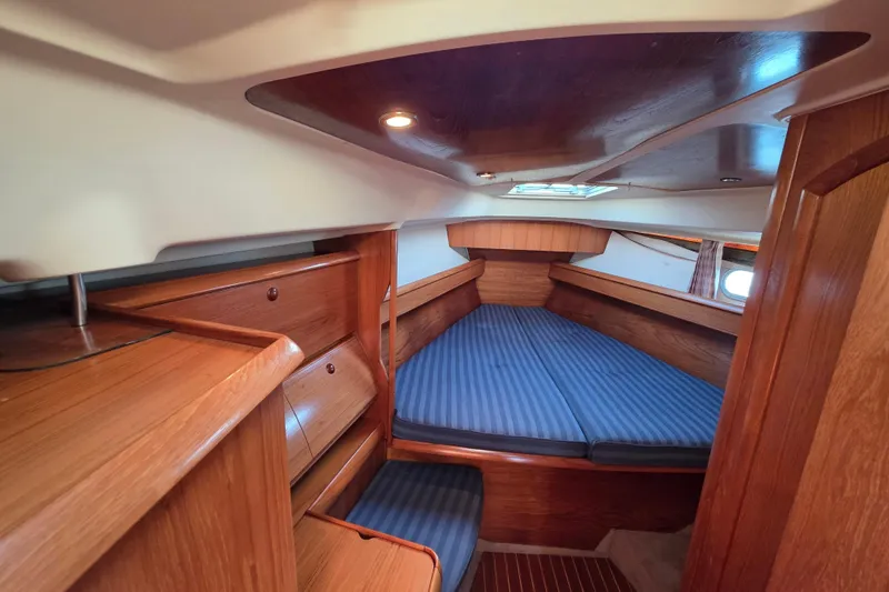 Hayabusa Yacht Photos Pics 1999 Jeanneau Sun Odyssey 40 DS cabin interior with wood finish and blue-striped bedding.