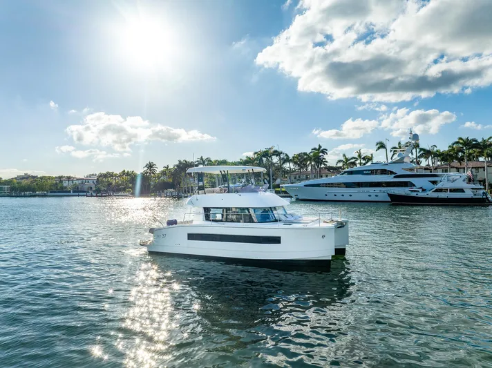 Floripa Yacht Photos Pics 2017 Fountaine Pajot MY 37 yacht on sunny water, with palm trees and boats in the background.