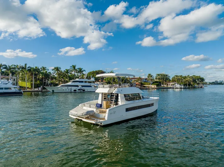 Floripa Yacht Photos Pics 2017 Fountaine Pajot MY 37 yacht cruising on a scenic waterway with palm trees.