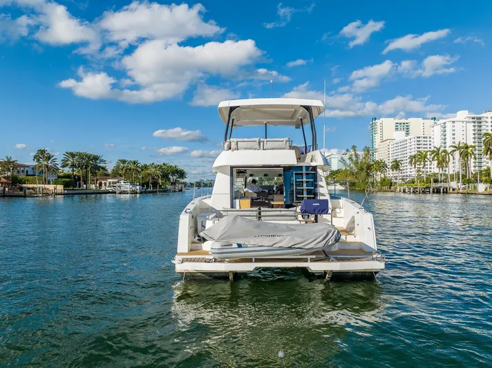 Floripa Yacht Photos Pics 2017 Fountaine Pajot MY 37 yacht on a sunny waterway with palm trees and buildings.