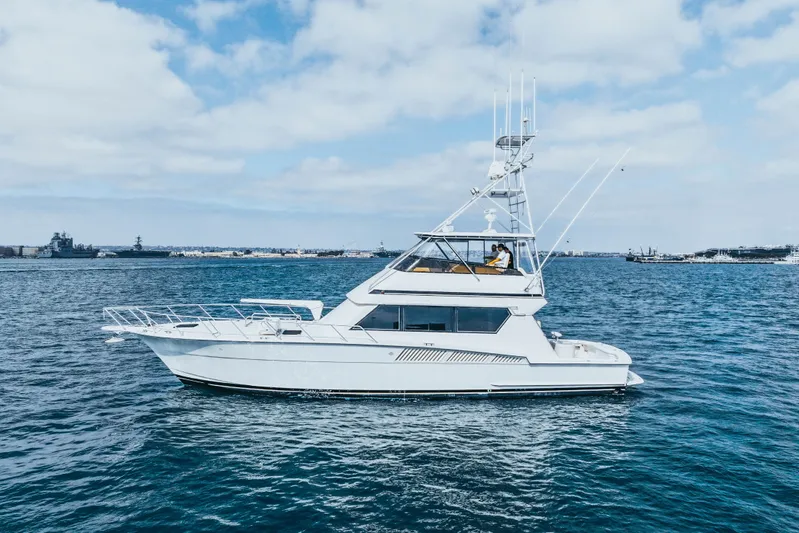 Bloodline Yacht Photos Pics 1990 Hatteras 58 Convertible yacht cruising on open water under a partly cloudy sky.