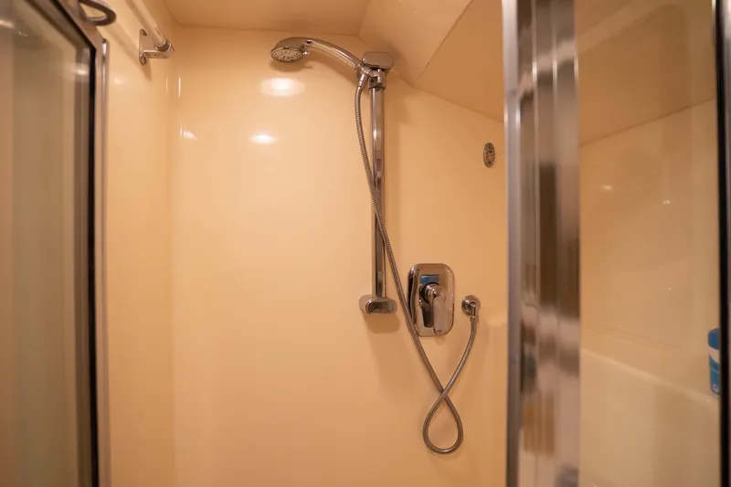 Bloodline Yacht Photos Pics Shower area in 1990 Hatteras 58 Convertible yacht, featuring chrome fixtures and beige walls.