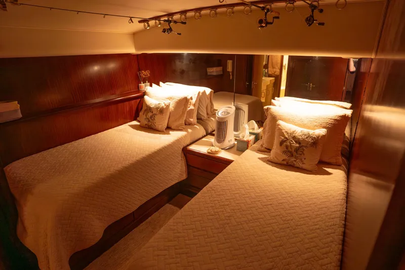 Bloodline Yacht Photos Pics Cozy twin bedroom in 1990 Hatteras 58 Convertible yacht with warm lighting.