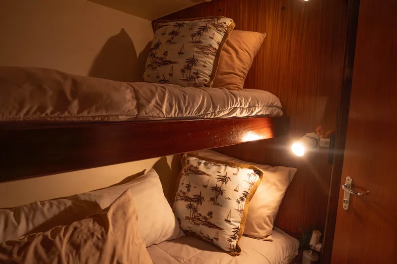 Bloodline Yacht Photos Pics Cozy bunk beds in a 1990 Hatteras 58 Convertible yacht cabin, warm lighting.