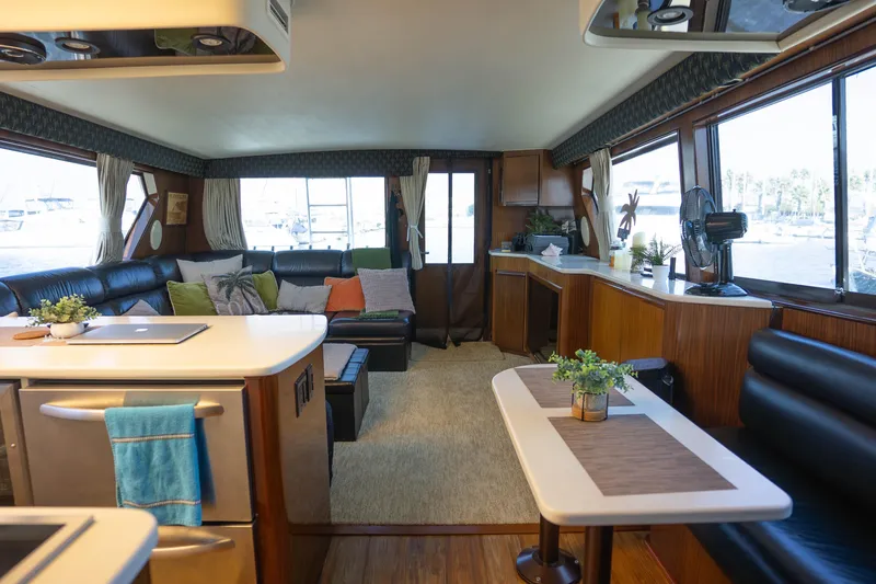 Bloodline Yacht Photos Pics Luxurious interior of a 1990 Hatteras 58 Convertible yacht with modern furnishings and large windows.