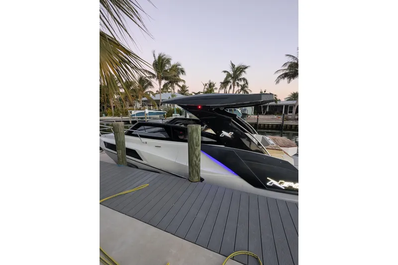 Mbvip Yacht Photos Pics 2023 NX Boats 340 Sport Coupe docked near palm trees at sunset.