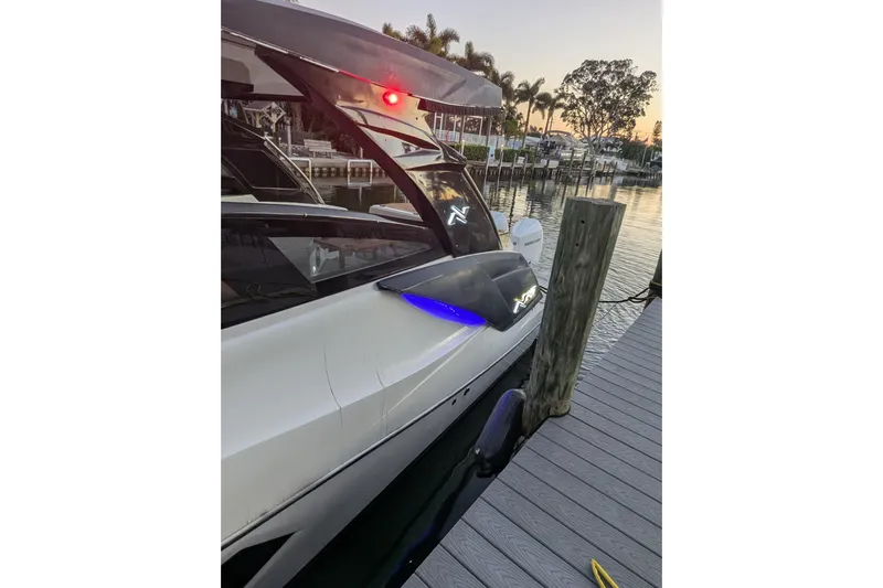 Mbvip Yacht Photos Pics 2023 NX Boats 340 Sport Coupe docked at sunset, featuring sleek design and blue lighting.