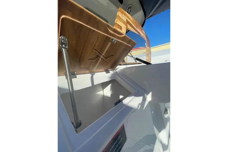 Mbvip Yacht Photos Pics 2023 NX Boats 340 Sport Coupe storage compartment with wooden lid open under clear blue sky.