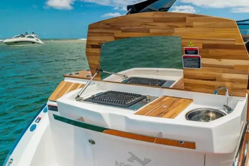 Mbvip Yacht Photos Pics 2023 NX Boats 340 Sport Coupe with outdoor kitchen on a sunny day.