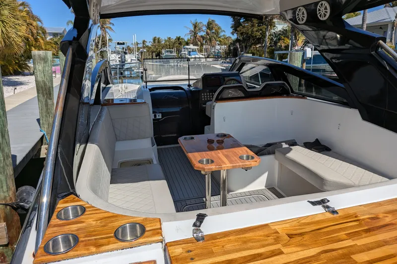 Mbvip Yacht Photos Pics 2023 NX Boats 340 Sport Coupe interior with seating and wooden table, docked at marina.