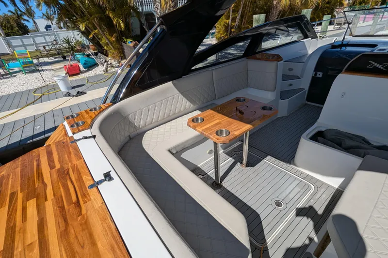 Mbvip Yacht Photos Pics 2023 NX Boats 340 Sport Coupe interior with elegant seating and wooden table.