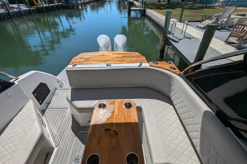 Mbvip Yacht Photos Pics 2023 NX Boats 340 Sport Coupe interior with elegant seating and wooden table by the water.
