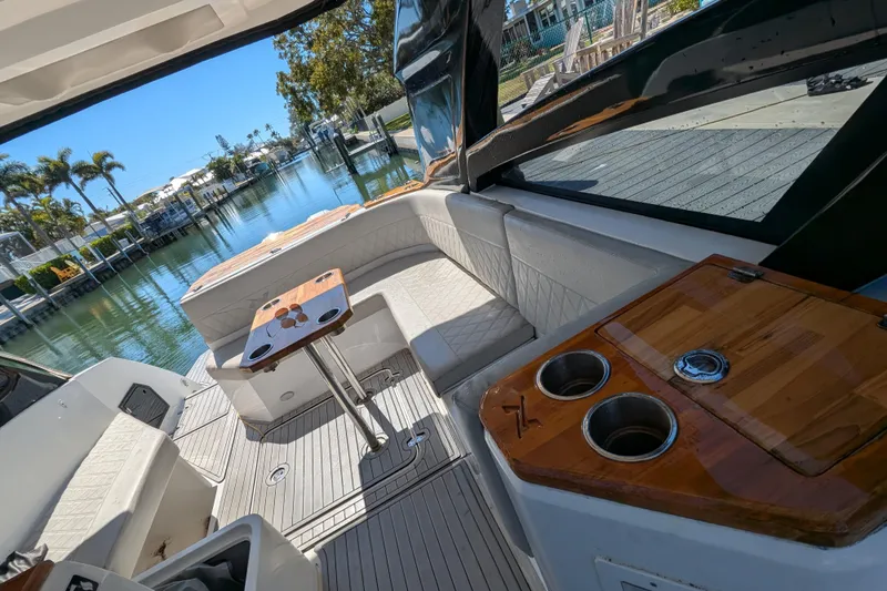 Mbvip Yacht Photos Pics 2023 NX Boats 340 Sport Coupe interior with seating and table, overlooking a serene waterfront.