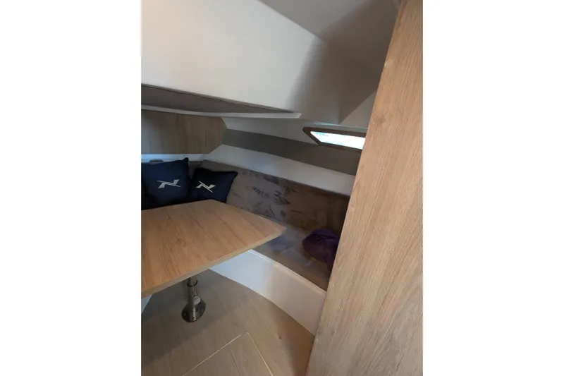 Mbvip Yacht Photos Pics 2023 NX Boats 340 Sport Coupe interior cabin with wooden table and seating area.