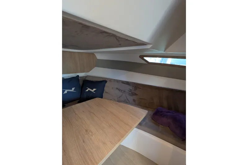 Mbvip Yacht Photos Pics Interior of 2023 NX Boats 340 Sport Coupe with wooden table and cushions.