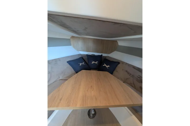 Mbvip Yacht Photos Pics Interior of 2023 NX Boats 340 Sport Coupe with wooden table and cushions.