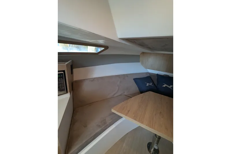 Mbvip Yacht Photos Pics 2023 NX Boats 340 Sport Coupe interior with cozy seating and wooden table.