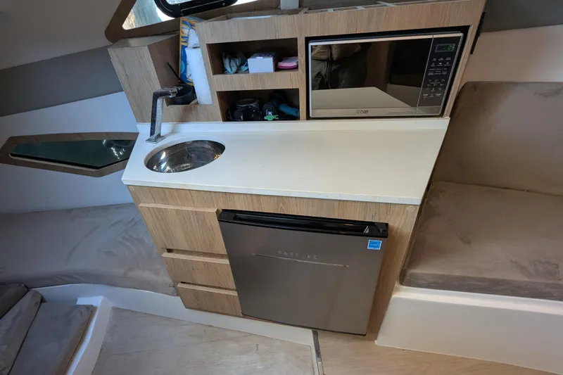 Mbvip Yacht Photos Pics Compact kitchenette in 2023 NX Boats 340 Sport Coupe with sink, microwave, and fridge.