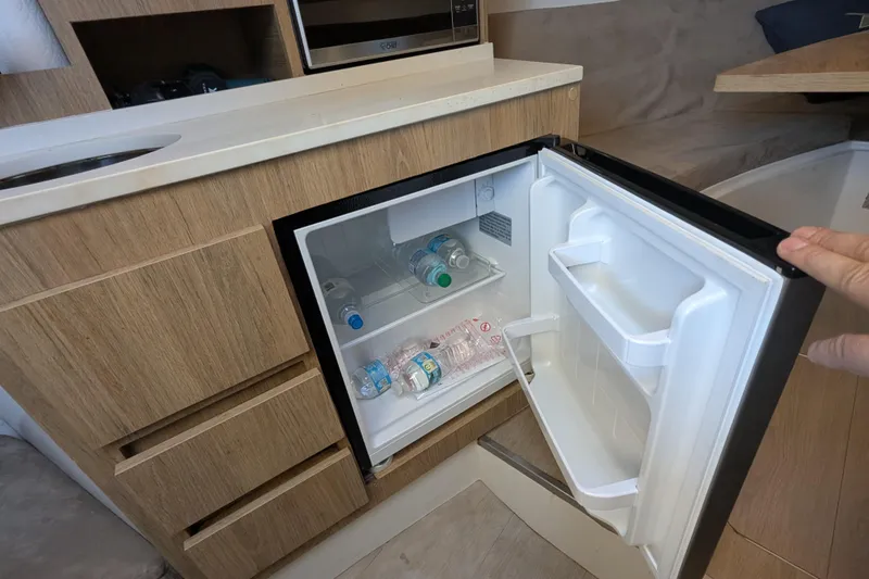 Mbvip Yacht Photos Pics Compact fridge in 2023 NX Boats 340 Sport Coupe, stocked with water bottles.