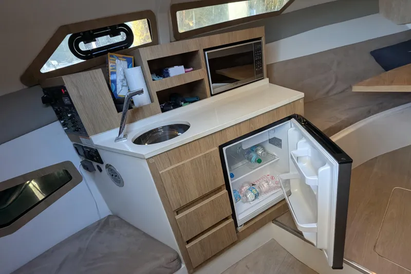 Mbvip Yacht Photos Pics Interior of 2023 NX Boats 340 Sport Coupe with kitchenette and open mini fridge.