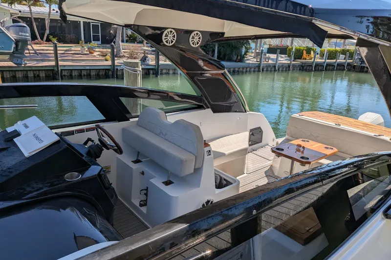 Mbvip Yacht Photos Pics 2023 NX Boats 340 Sport Coupe interior with seating and table, docked by the water.