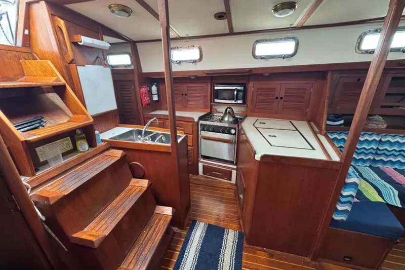 Bittersweet Yacht Photos Pics 1989 Tartan 4100 yacht interior with wooden cabinetry, kitchen, and seating area.