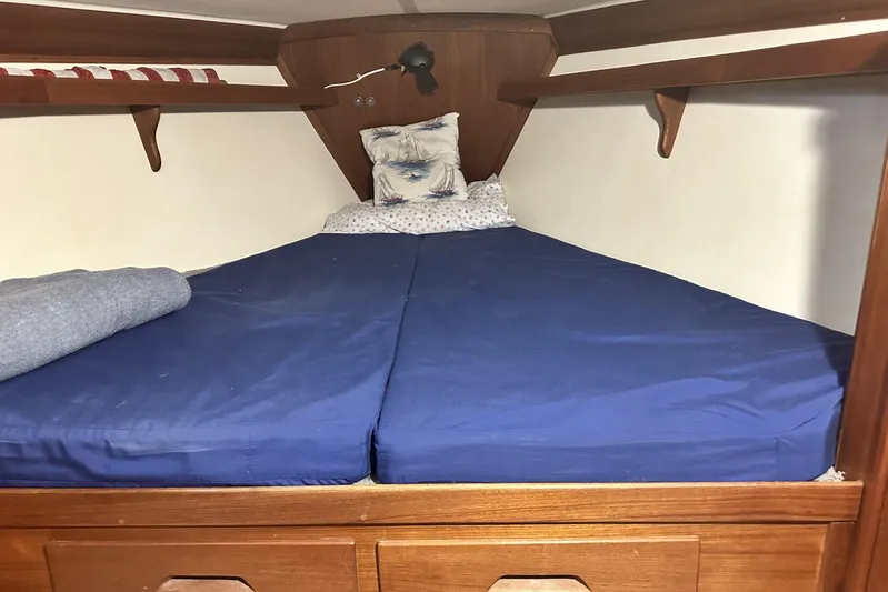 Bittersweet Yacht Photos Pics Cozy cabin bed in 1998 Tartan 4100 sailboat with blue bedding and wooden shelves.