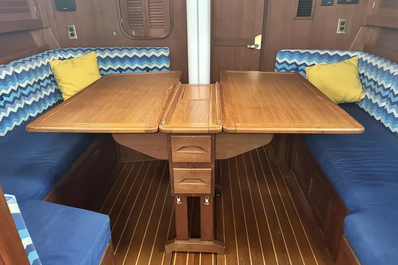 Bittersweet Yacht Photos Pics Interior of 1998 Tartan 4100 sailboat with wooden table, blue seating, and chevron-patterned cushions.