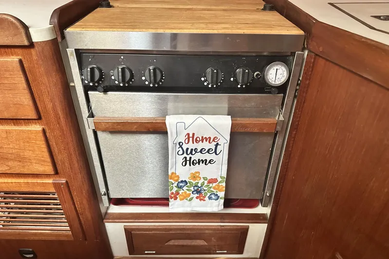 Bittersweet Yacht Photos Pics 1998 Tartan 4100 yacht kitchen with oven, wooden cabinetry, and "Home Sweet Home" towel.