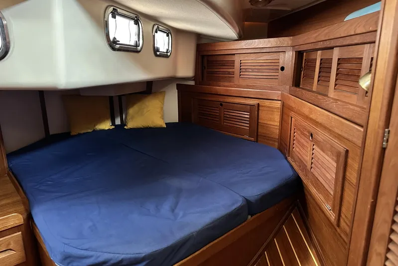 Bittersweet Yacht Photos Pics Cozy cabin interior of 1998 Tartan 4100 sailboat with wooden finish and blue bedding.