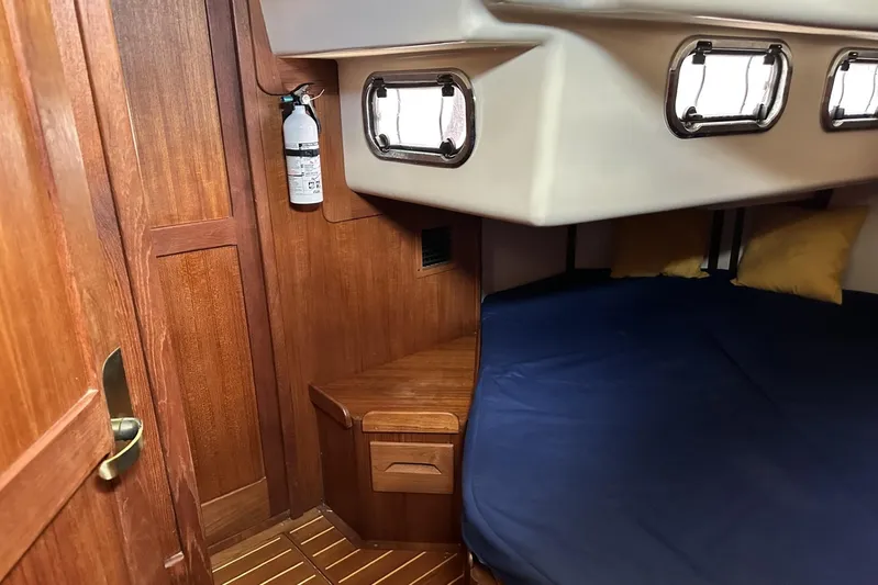Bittersweet Yacht Photos Pics Cozy cabin interior of 1998 Tartan 4100 sailboat with wooden finish and blue bedding.