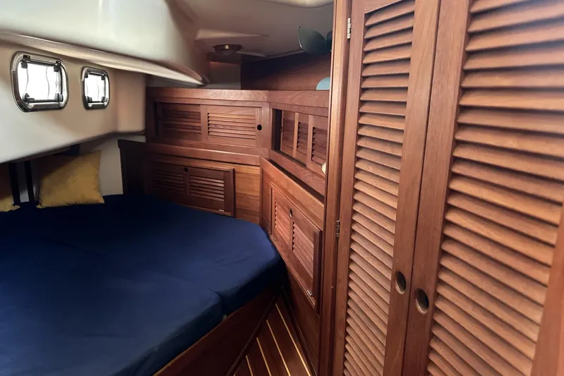 Bittersweet Yacht Photos Pics Cozy cabin interior of 1998 Tartan 4100 sailboat with wooden furnishings and blue bedding.