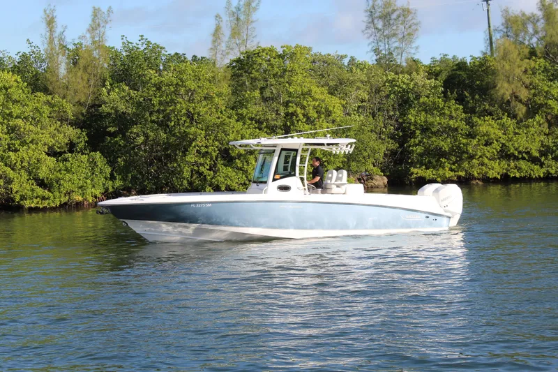 Better Than Most Yacht Photos Pics 2015 Boston Whaler 320 Outrage boat cruising on a calm river near lush greenery.