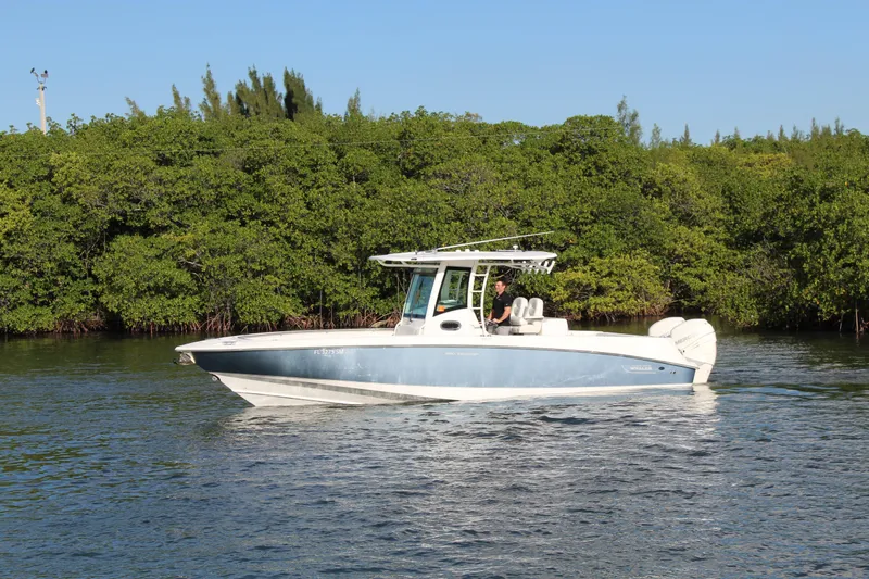 Better Than Most Yacht Photos Pics 2015 Boston Whaler 320 Outrage boat cruising on calm water near lush greenery.