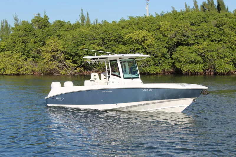Better Than Most Yacht Photos Pics 2015 Boston Whaler 320 Outrage boat on calm water near lush greenery.