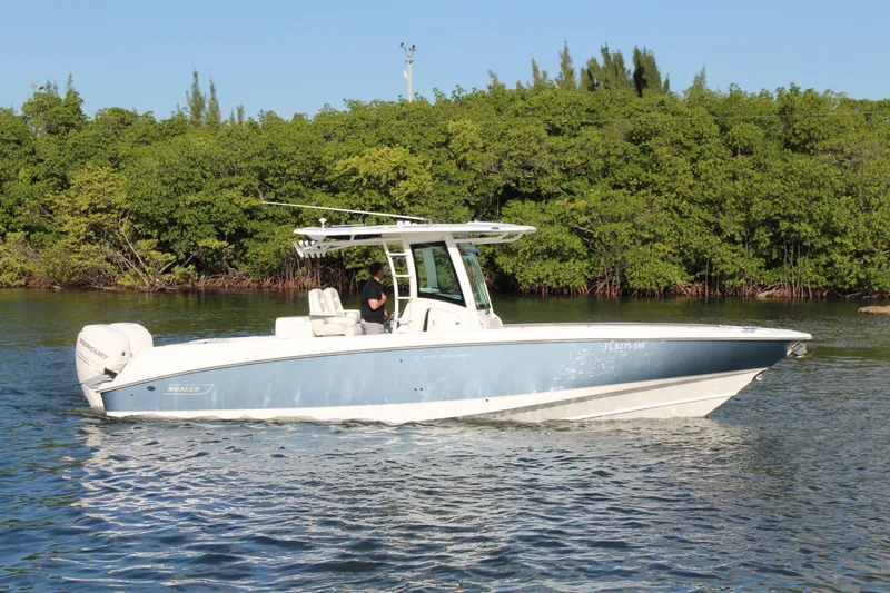 Better Than Most Yacht Photos Pics 2015 Boston Whaler 320 Outrage boat cruising on calm water near lush greenery.