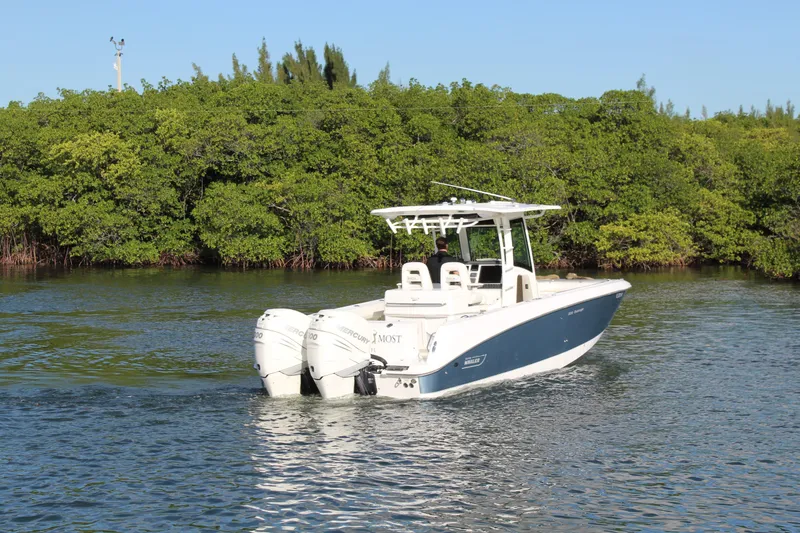 Better Than Most Yacht Photos Pics 2015 Boston Whaler 320 Outrage boat cruising near lush green shoreline.